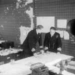 THE ROYAL NAVY DURING THE SECOND WORLD WAR (A 25742) Commander Cross, Staff Officer Convoys, (left) discussing a special convoy movement map with Captain Lake, RN, Duty Officer in the Operations Room at Derby House, Liverpool.