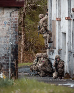 Urban combat: A soldier scrambles up a building wall while others provide protection